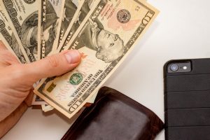 Hand holding US dollars various 50 banknotes with wallet and smartphone on a white background